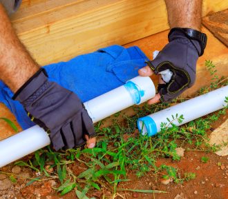 Installing plastic PVC pipes for construction of water system by plumbing contractor